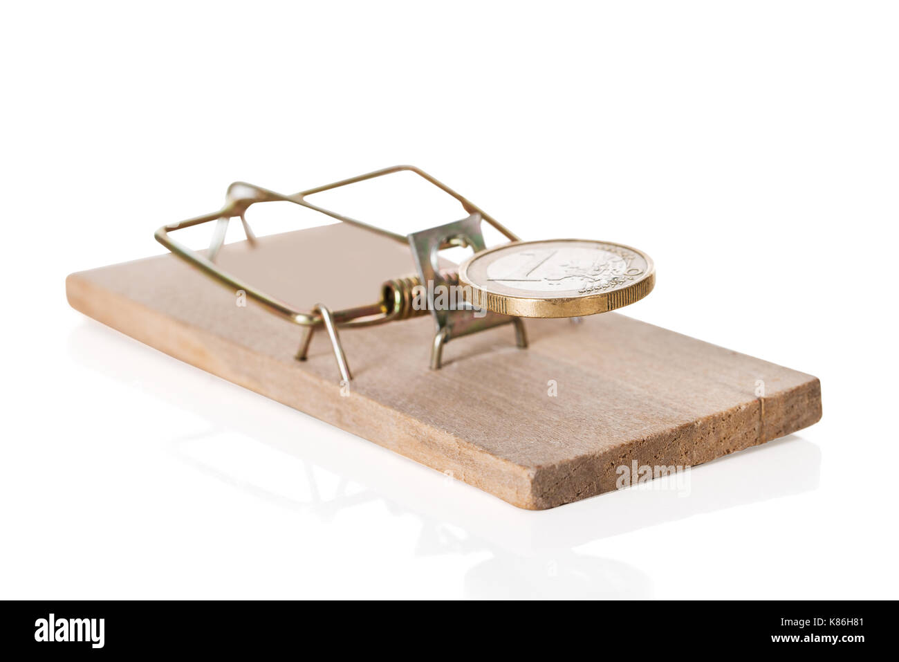 Primo piano della moneta sul mousetrap contro uno sfondo bianco Foto Stock