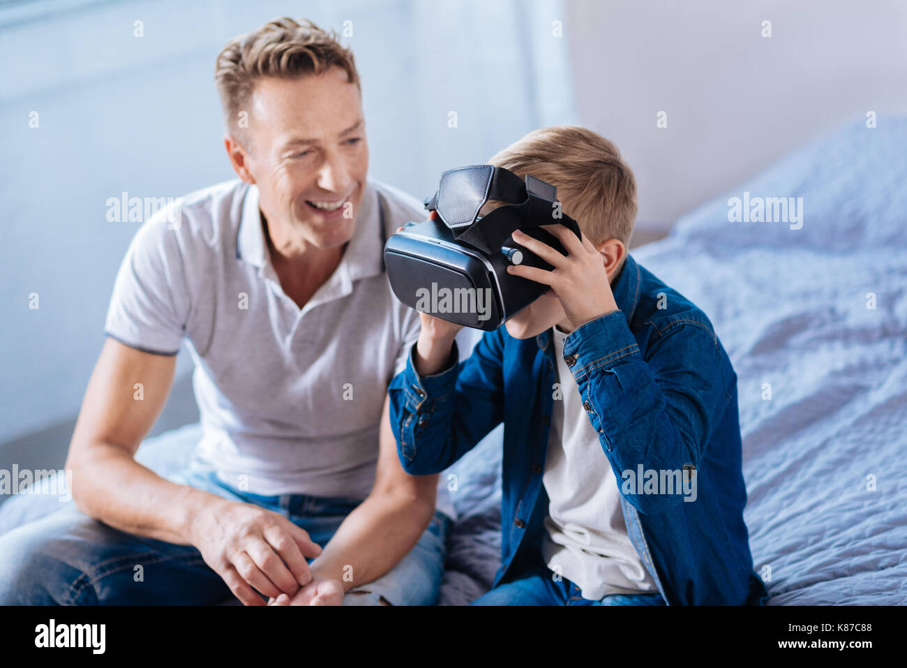 Allegro padre guarda il suo figlio prova auricolare vr Foto Stock
