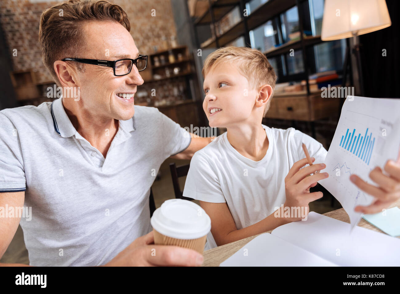 Pre-teen boy chiedendo a suo padre informazioni sui grafici sulla stampa Foto Stock