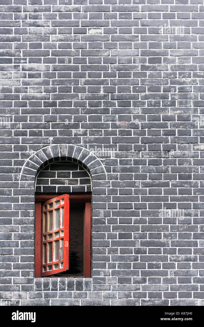 Piccola finestra rossa in un muro di mattoni Foto Stock