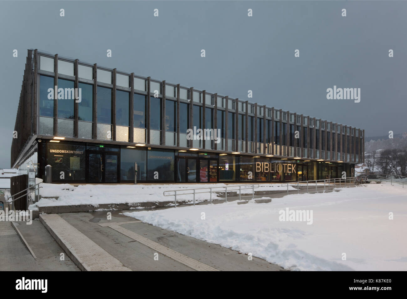 Principale facciata esterna con alette di legname, su terreni innevati sera d'inverno. Krona Knowledge & Centro Culturale, Kongsberg, Norvegia. Architetto: mecanoo + codice Arkite Foto Stock