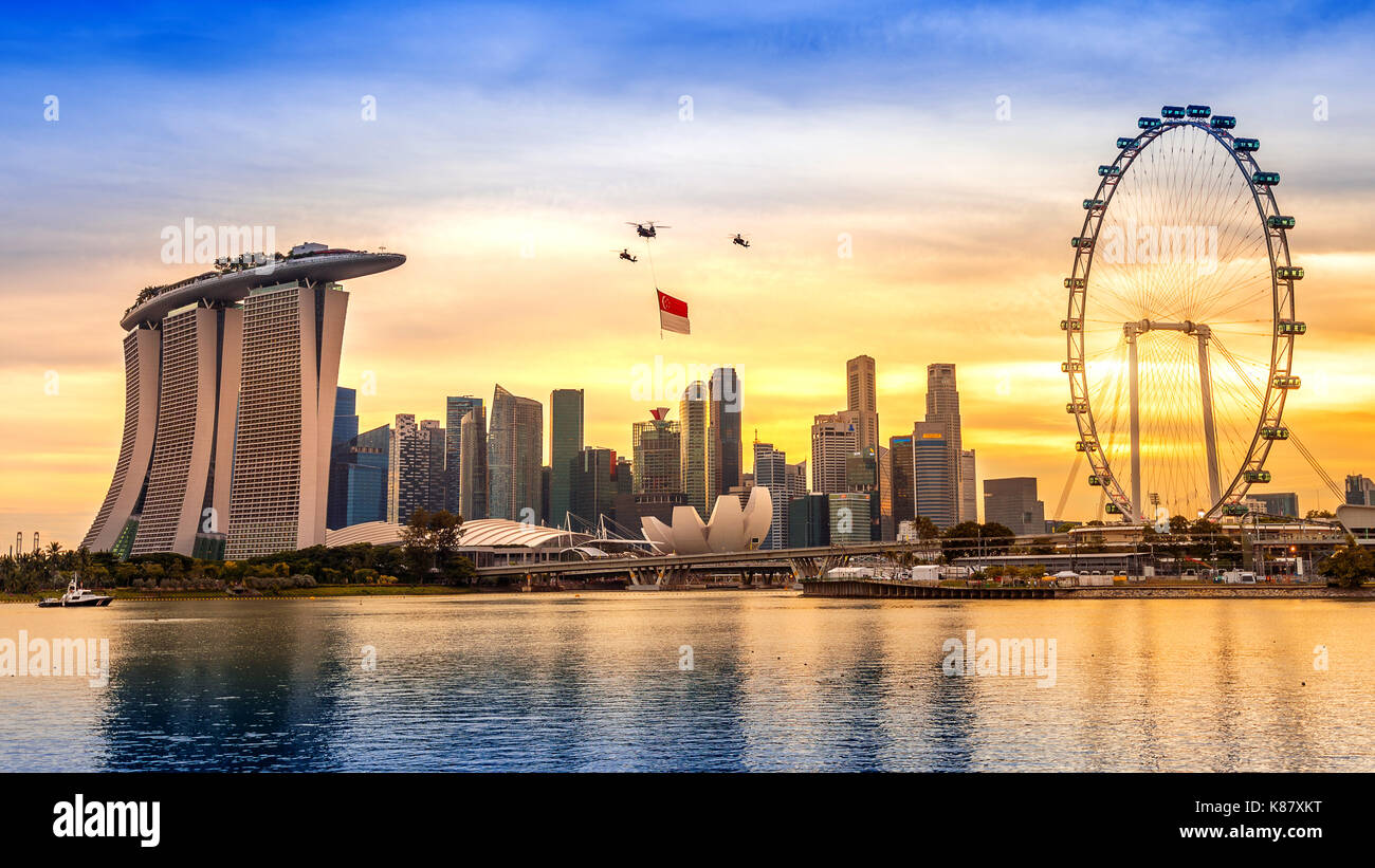 Singapore giornata nazionale elicottero appesa Bandiera di Singapore volando sopra la città. Foto Stock