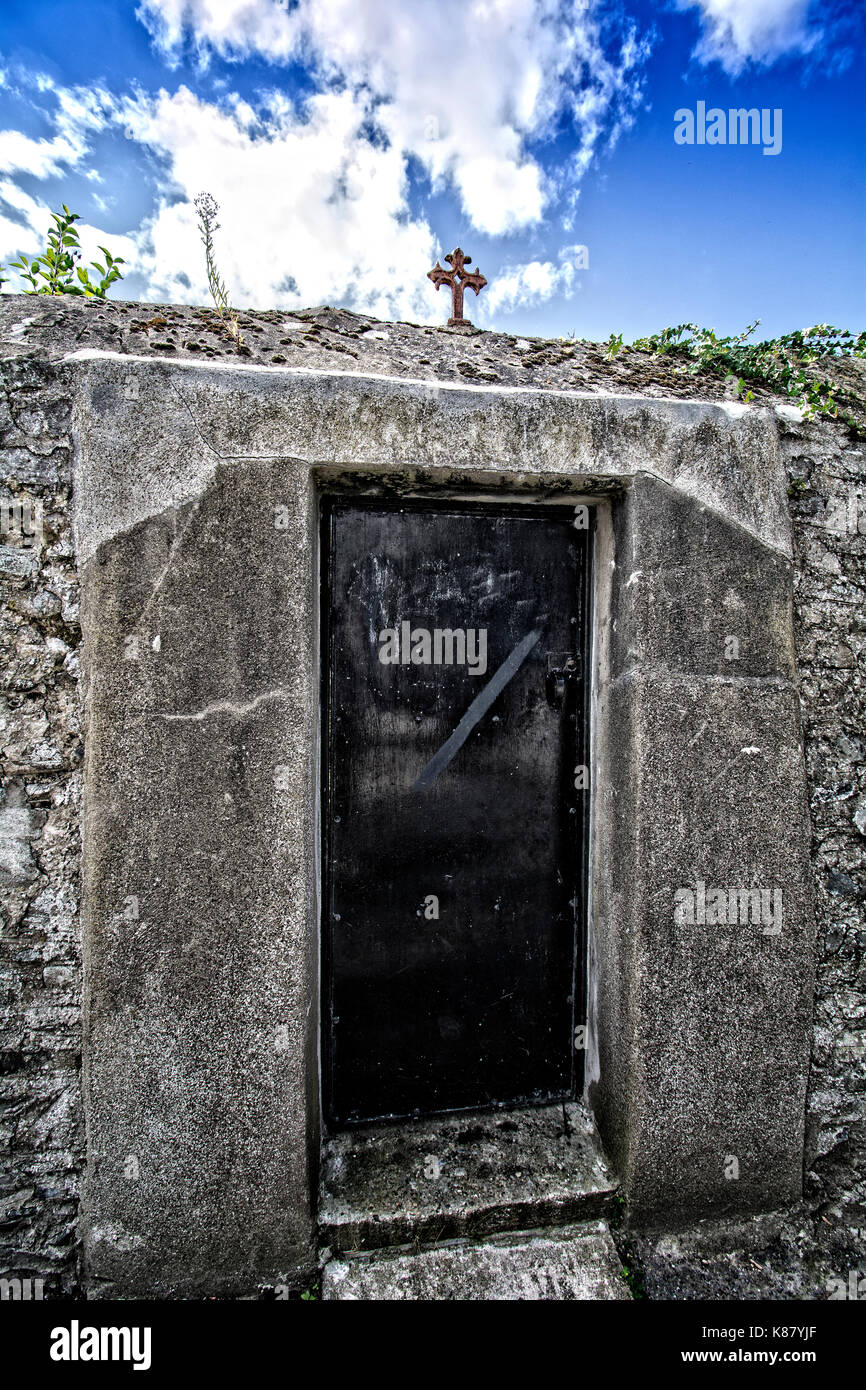 Una porta di metallo verniciato nero e una croce di ferro montata sopra segna la porta sul retro giardino di un convento Foto Stock