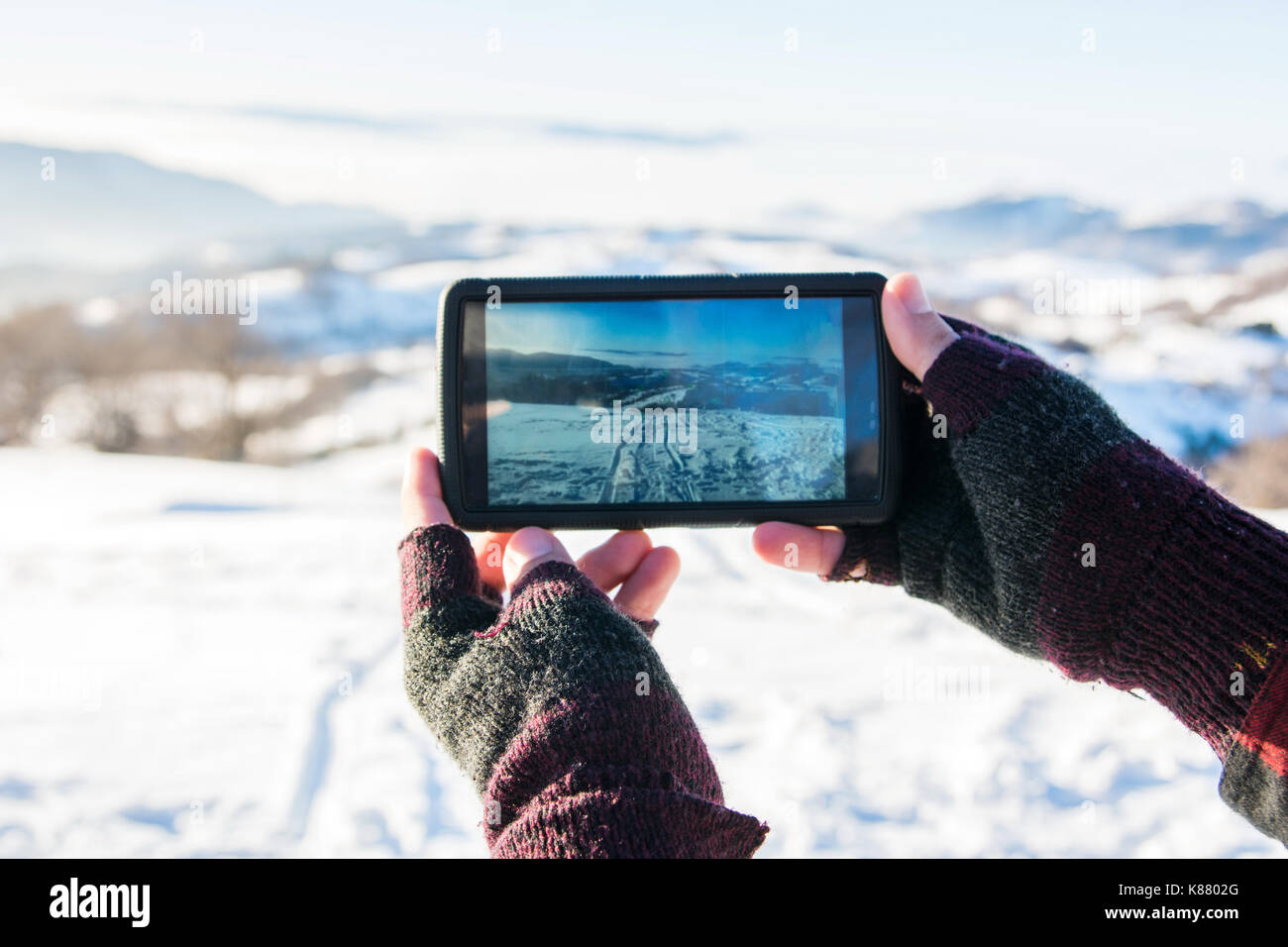 Uomo di scattare una foto con smart phone in inverno Foto Stock