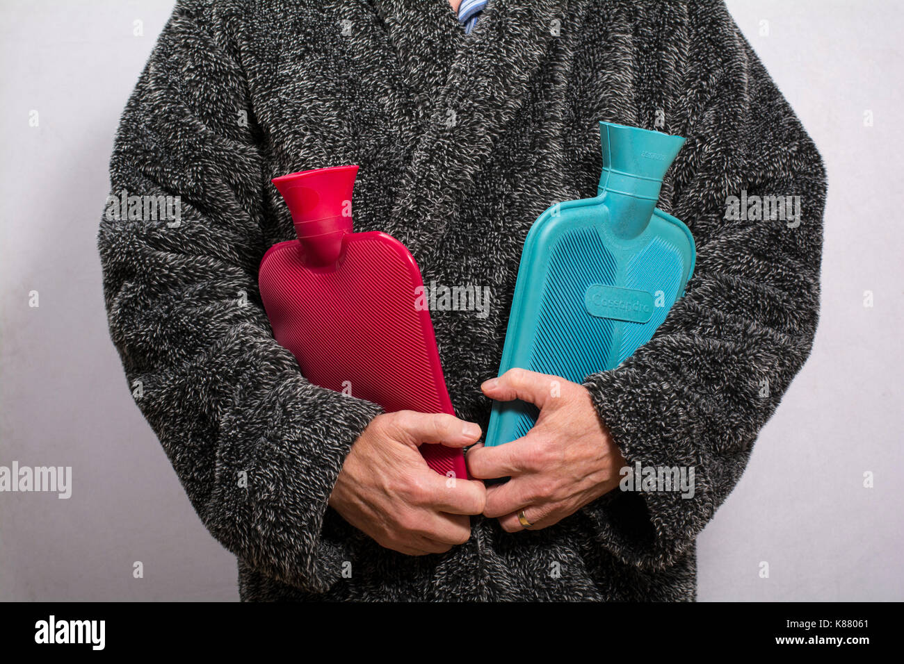 Uomo in un soffice vestaglia tenendo due bottiglie di acqua calda. Foto Stock