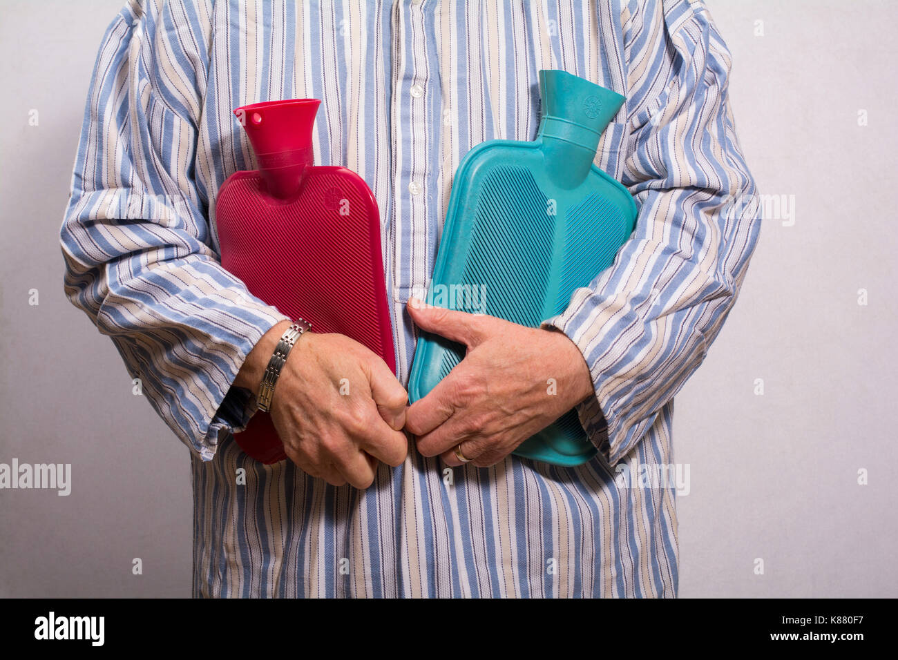 Uomo in una holding nightgown due bottiglie di acqua calda. Foto Stock