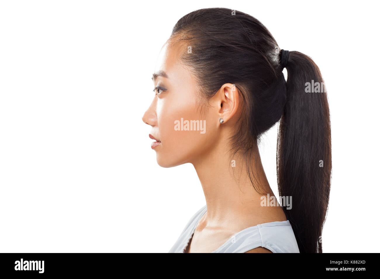 Closeup ritratto di Asian giovane donna nel profilo con coda di cavallo. Studo foto di Pretty girl conciate con nuova pelle e capelli scuri per diversi trattamenti di bellezza e Foto Stock