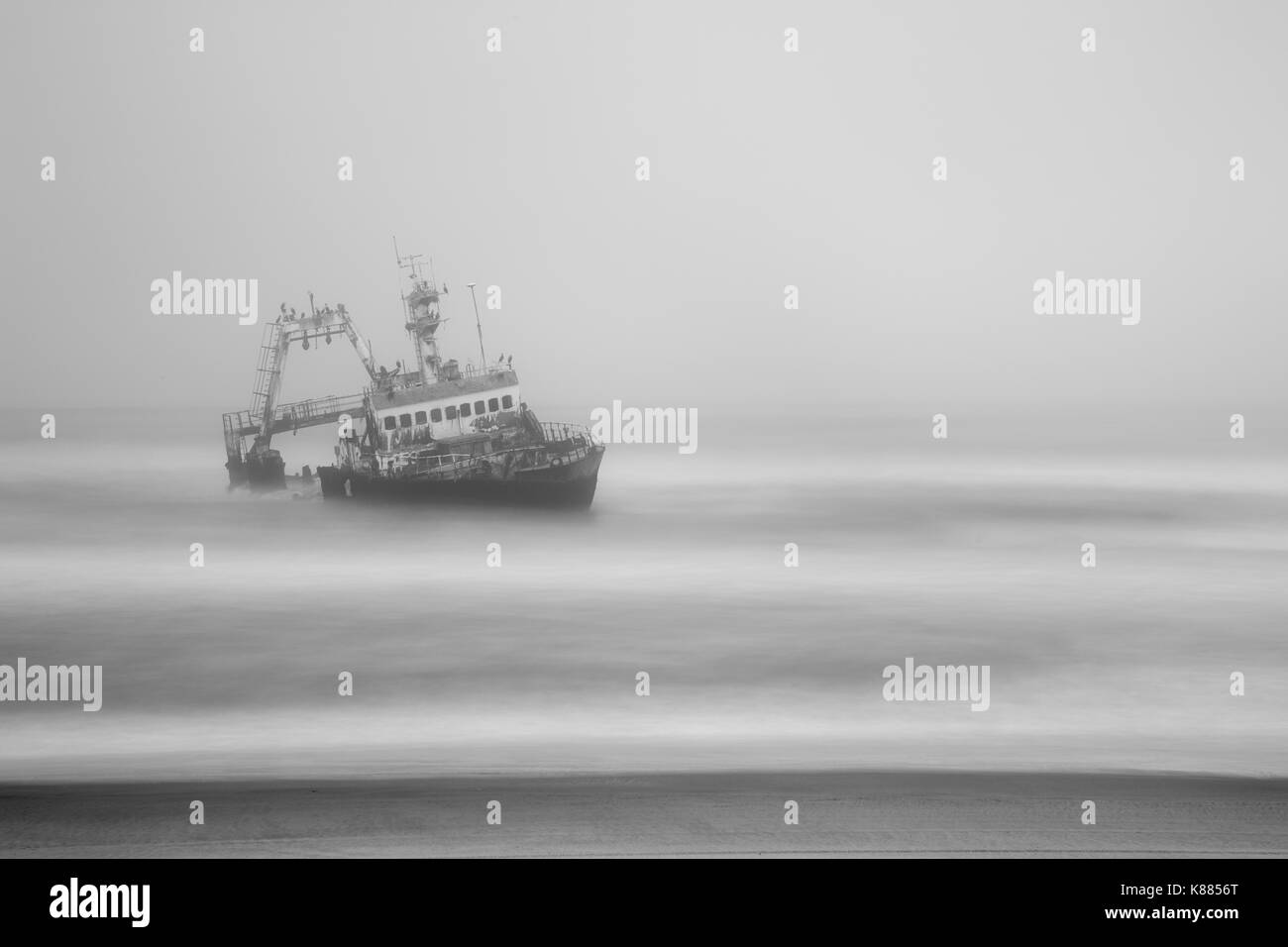 Barca naufragò. Un contenitore nave naufragata e spiaggiata nei fondali bassi in un mare tempestoso. vista dalla riva. Foto Stock