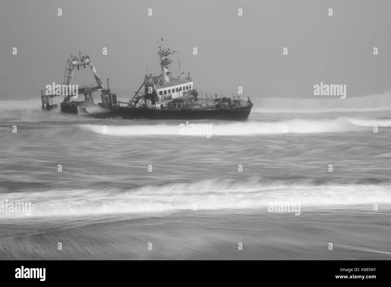Barca naufragò. Un contenitore nave naufragata e spiaggiata nei fondali bassi in un mare tempestoso. vista dalla riva. Foto Stock