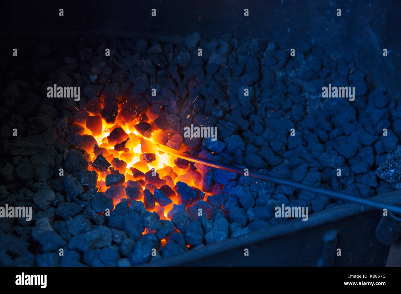 Un incandescente asta metallica in carboni caldi in un la fucina di fabbro ferraio di. Foto Stock