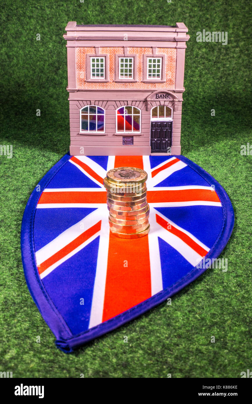 Un modello di banca per un Unione Jack, con nuovo sterling pound monete. Un concetto che raffigura il finanziamento di qualsiasi aspetto correlato del settore bancario nel Regno Unito. Foto Stock