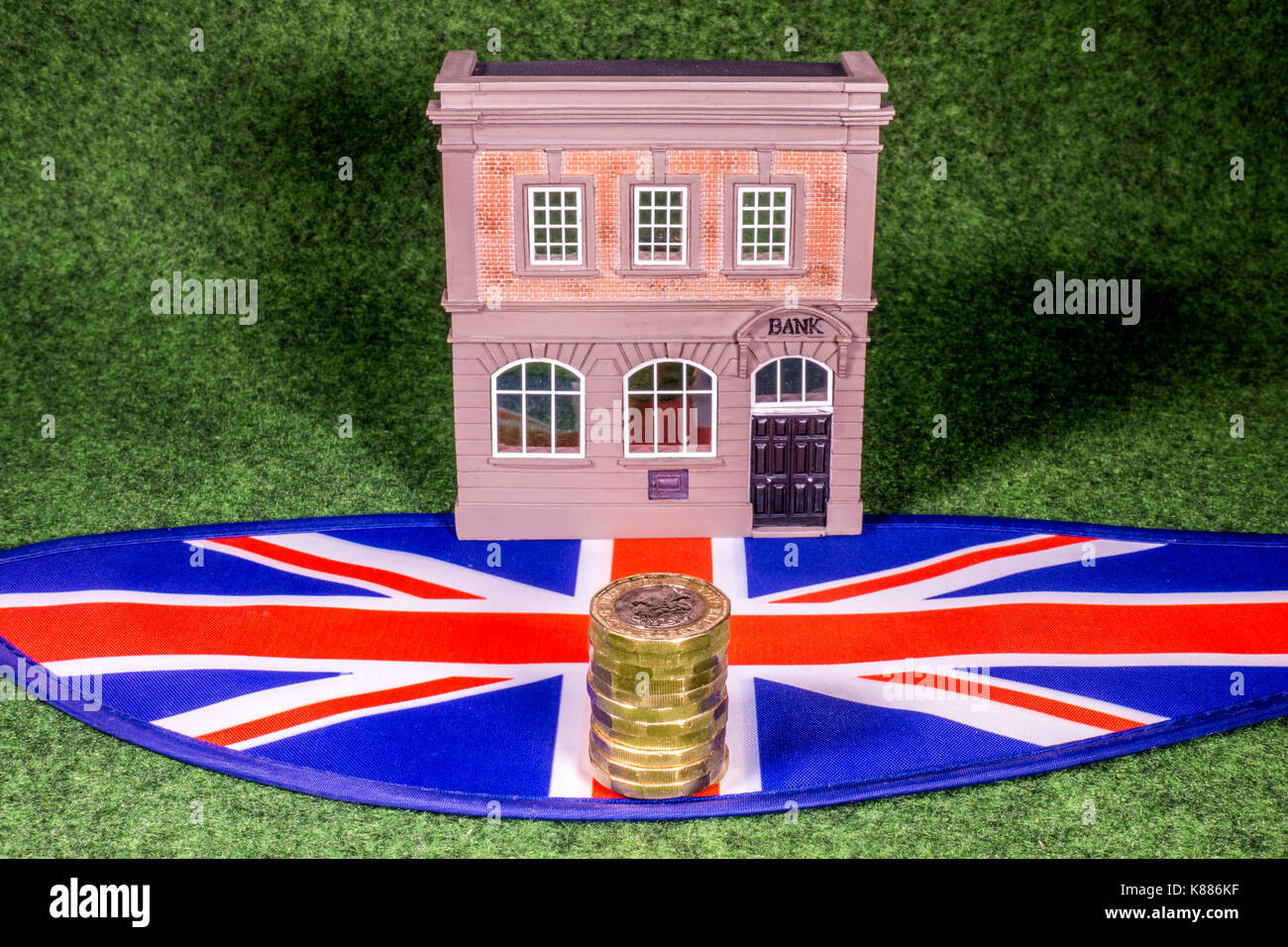 Un modello di banca per un Unione Jack, con nuovo sterling pound monete. Un concetto che raffigura il finanziamento di qualsiasi aspetto correlato del settore bancario nel Regno Unito. Foto Stock