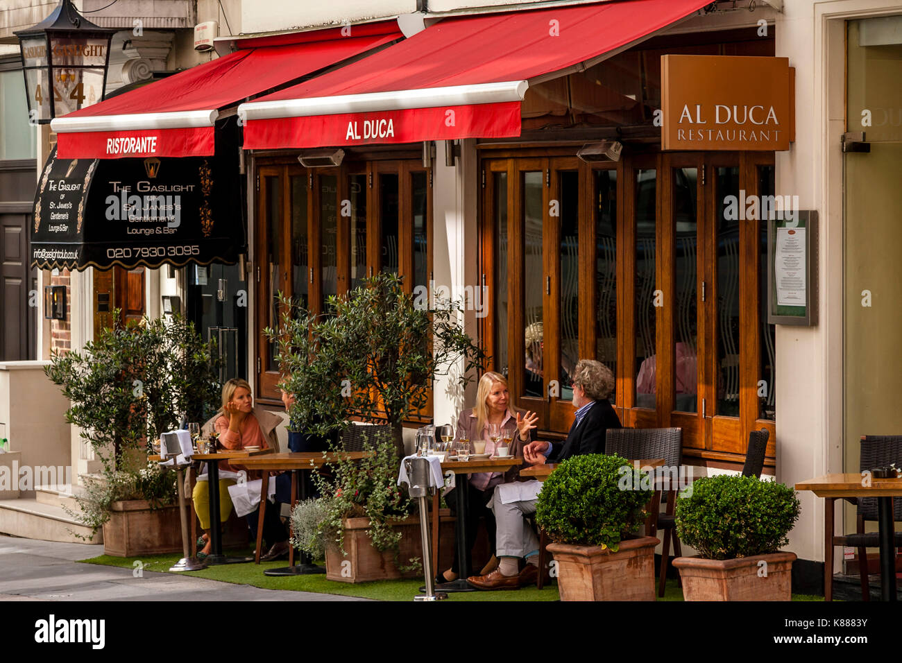 La gente seduta fuori al duca ristorante nel Duca di York Street, St James's, London, Regno Unito Foto Stock