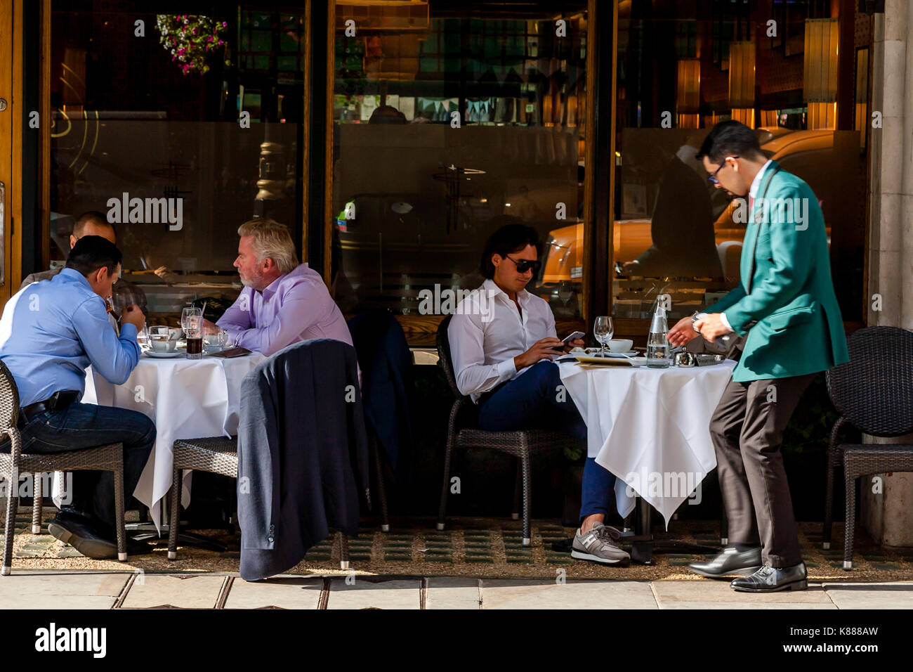 Un gruppo di ben vestito uomini seduti fuori Franco's Restaurant, Jermyn Street, Mayfair, London, Regno Unito Foto Stock