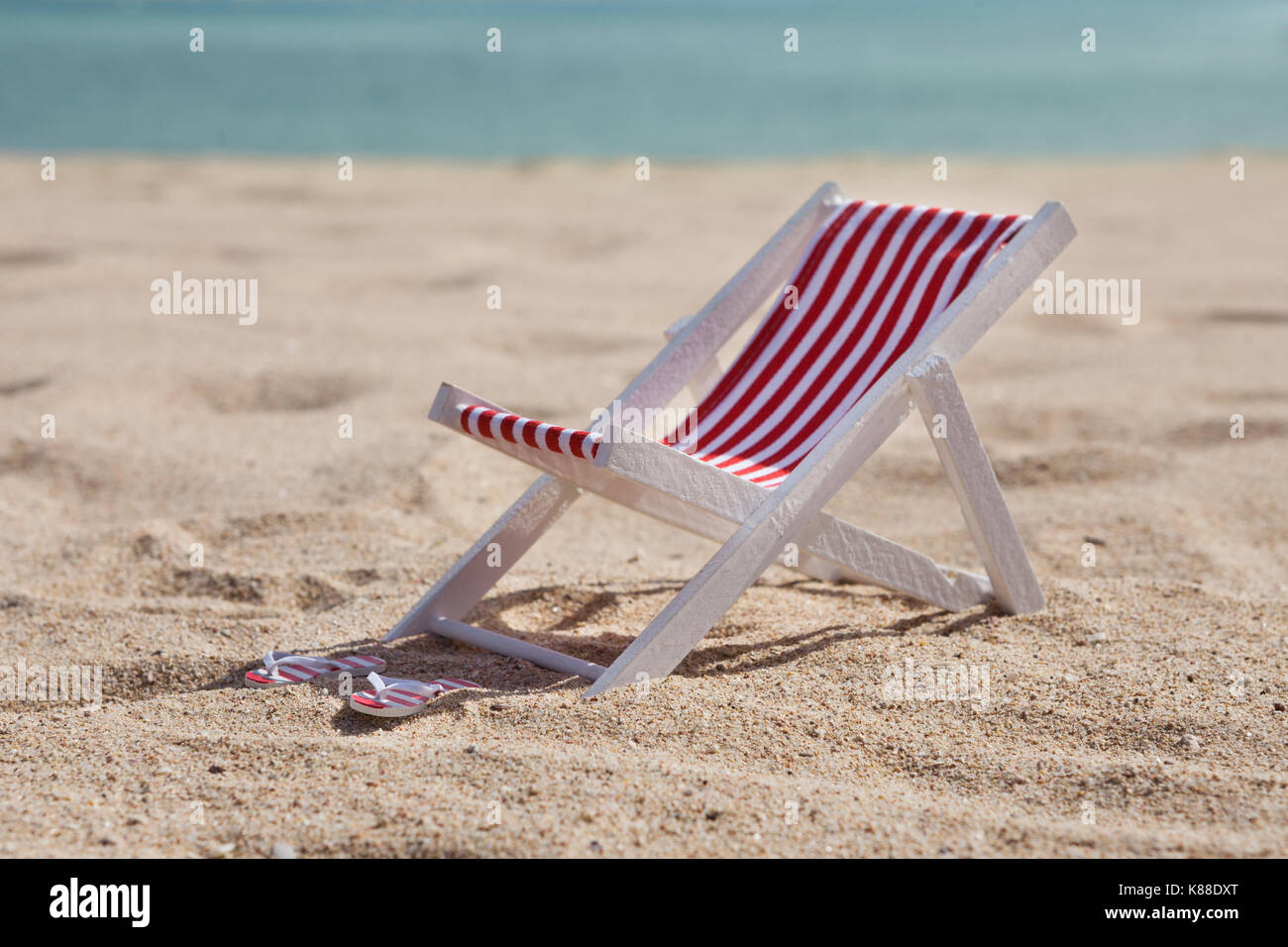 Sdraio sulla spiaggia e flip-flop sulla spiaggia sabbiosa Foto Stock