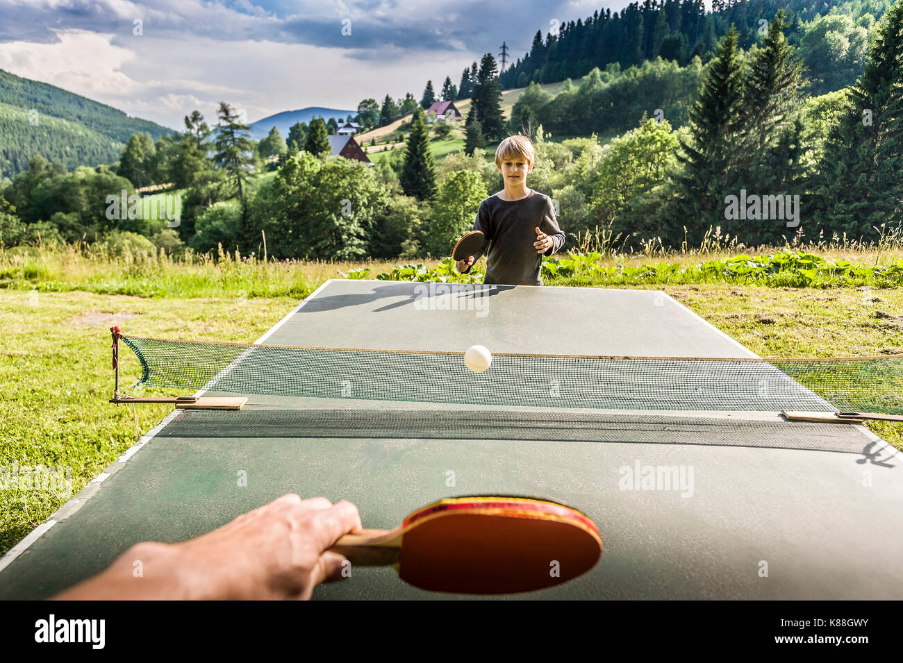 Scuola ragazzo giocando a ping-pong per esterno Foto Stock