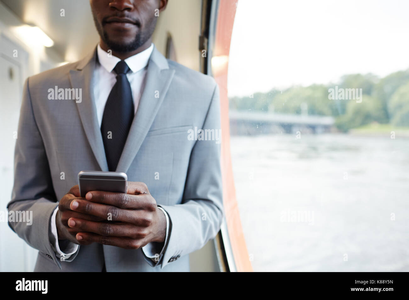 African-imprenditore americano con lo smartphone texting durante il suo viaggio Foto Stock