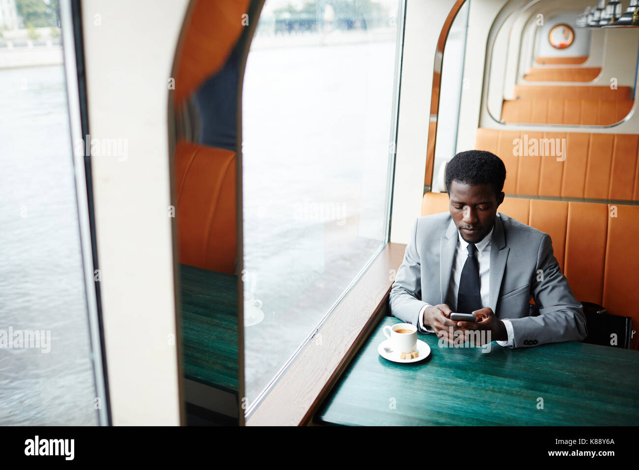 Uomo elegante texting in smartphone durante l udienza del caffè dalla tazza di caffè Foto Stock