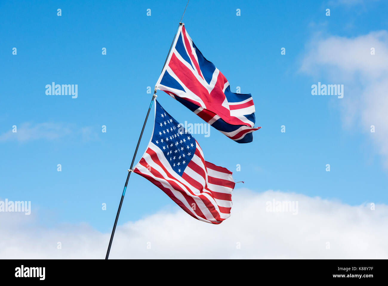 Union Jack e bandiera americana nel vento contro un cielo blu Foto Stock