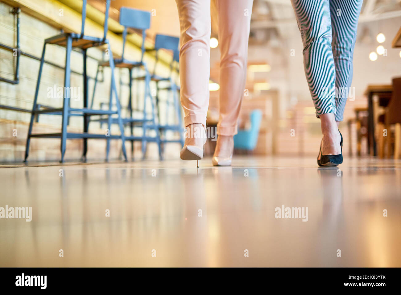 Due giovani donne in leggins e scarpe con i tacchi alti a piedi lungo  bancone con sedie per bar Foto stock - Alamy