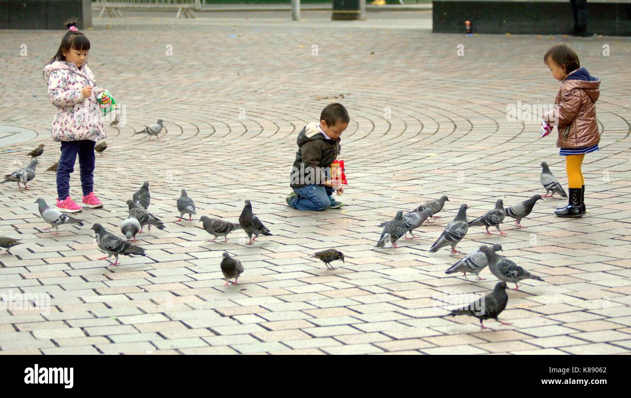 I bambini cinesi feed piccioni Snack di patate in St Enoch Square glasgow Foto Stock