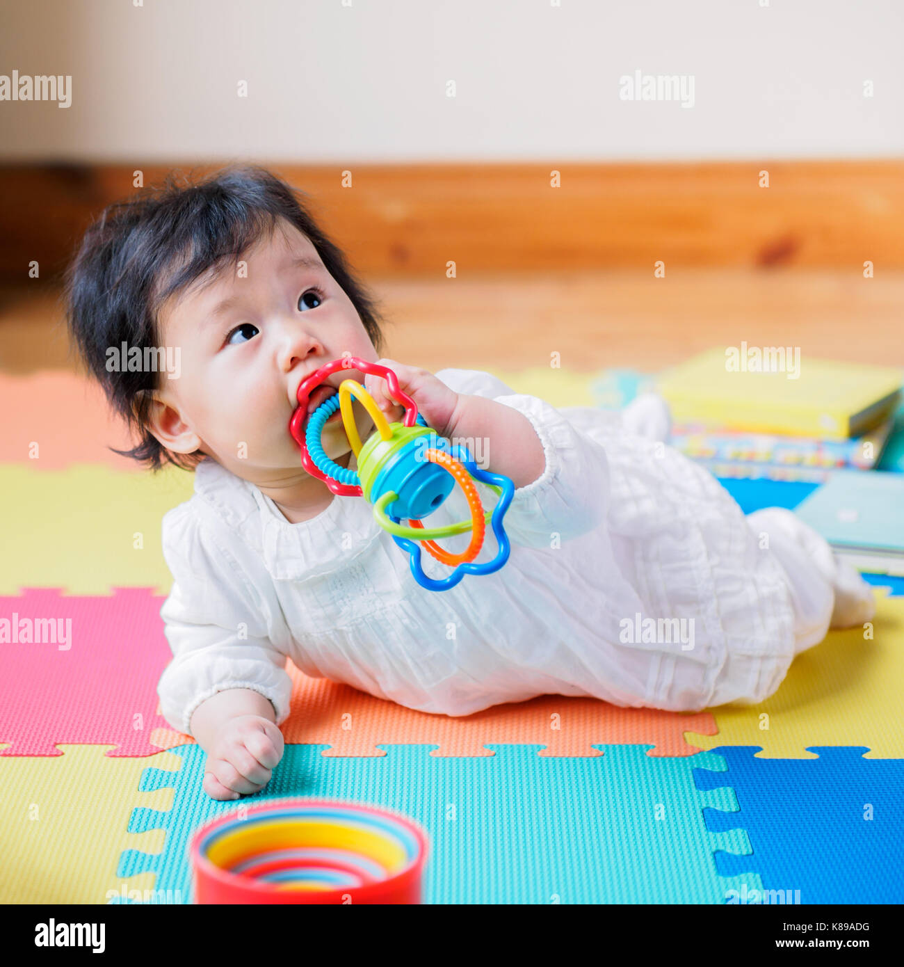 La dentizione asiatici Baby girl strisciando sul tappeto gioco Foto Stock