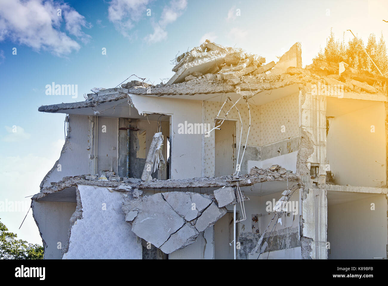 La rovina di un parzialmente demolito palazzo residenziale (piano superiore) davanti a un cielo blu con nuvole bianche Foto Stock