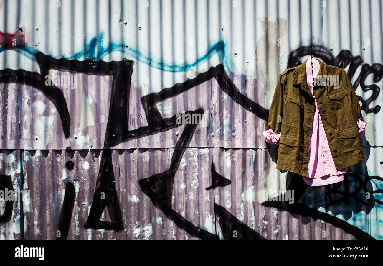 Abbigliamento vintage è visualizzato contro i graffiti a Columbia road flower market Foto Stock