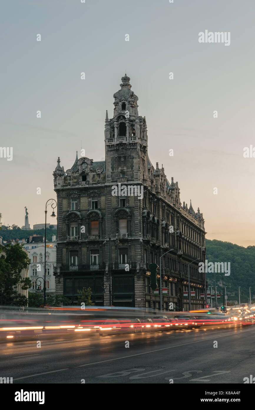 Lighttrails delle vetture in movimento nella parte anteriore di un vecchio edificio storico di Budapest accanto al ponte Elisabetta, Ungheria. Foto Stock