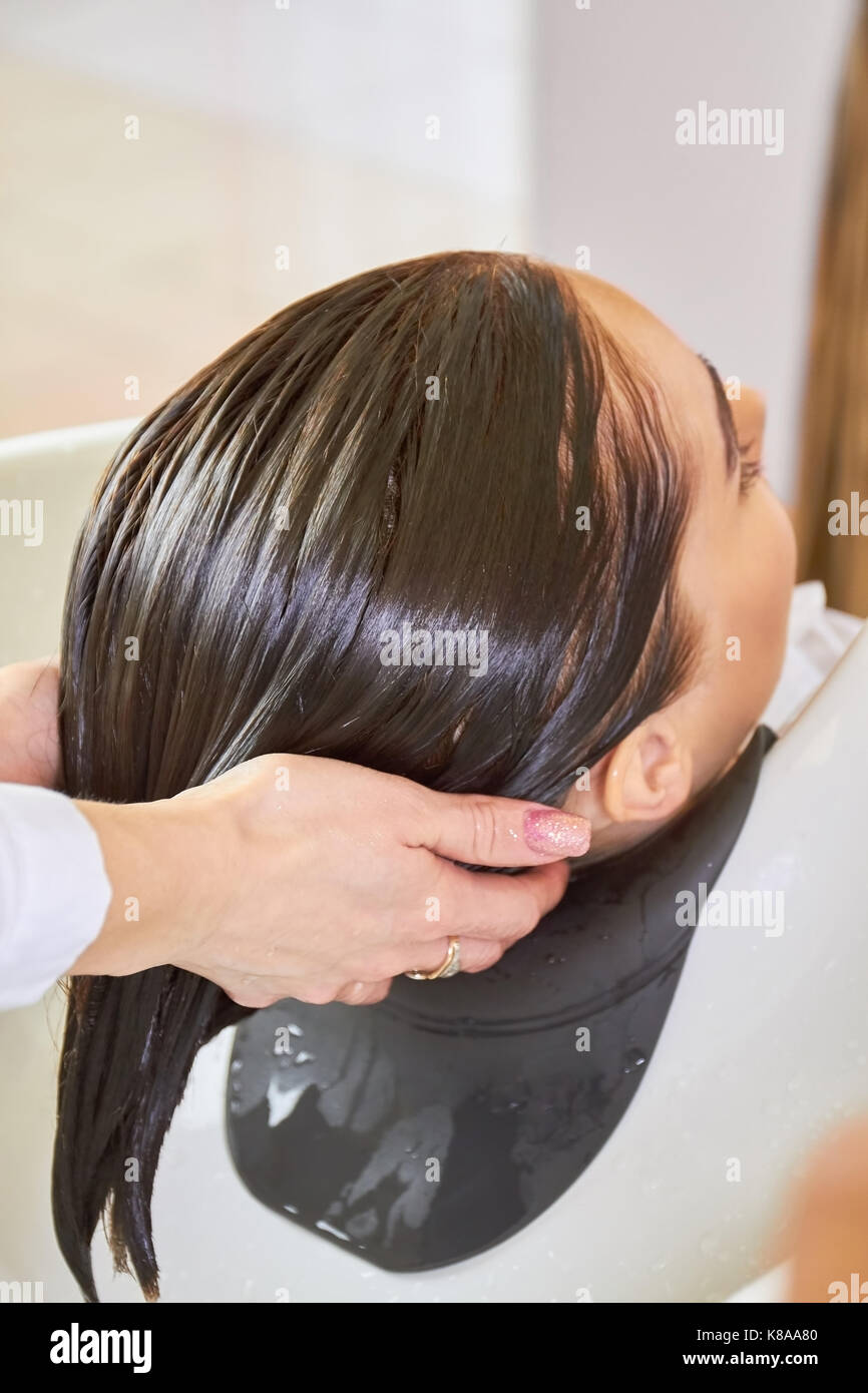 Le mani di estetista, capelli bagnati. Foto Stock