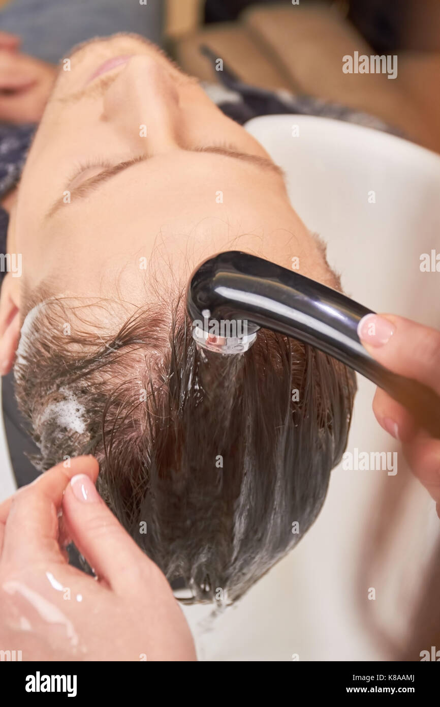 Barbiere risciacquare i capelli, vicino. Foto Stock