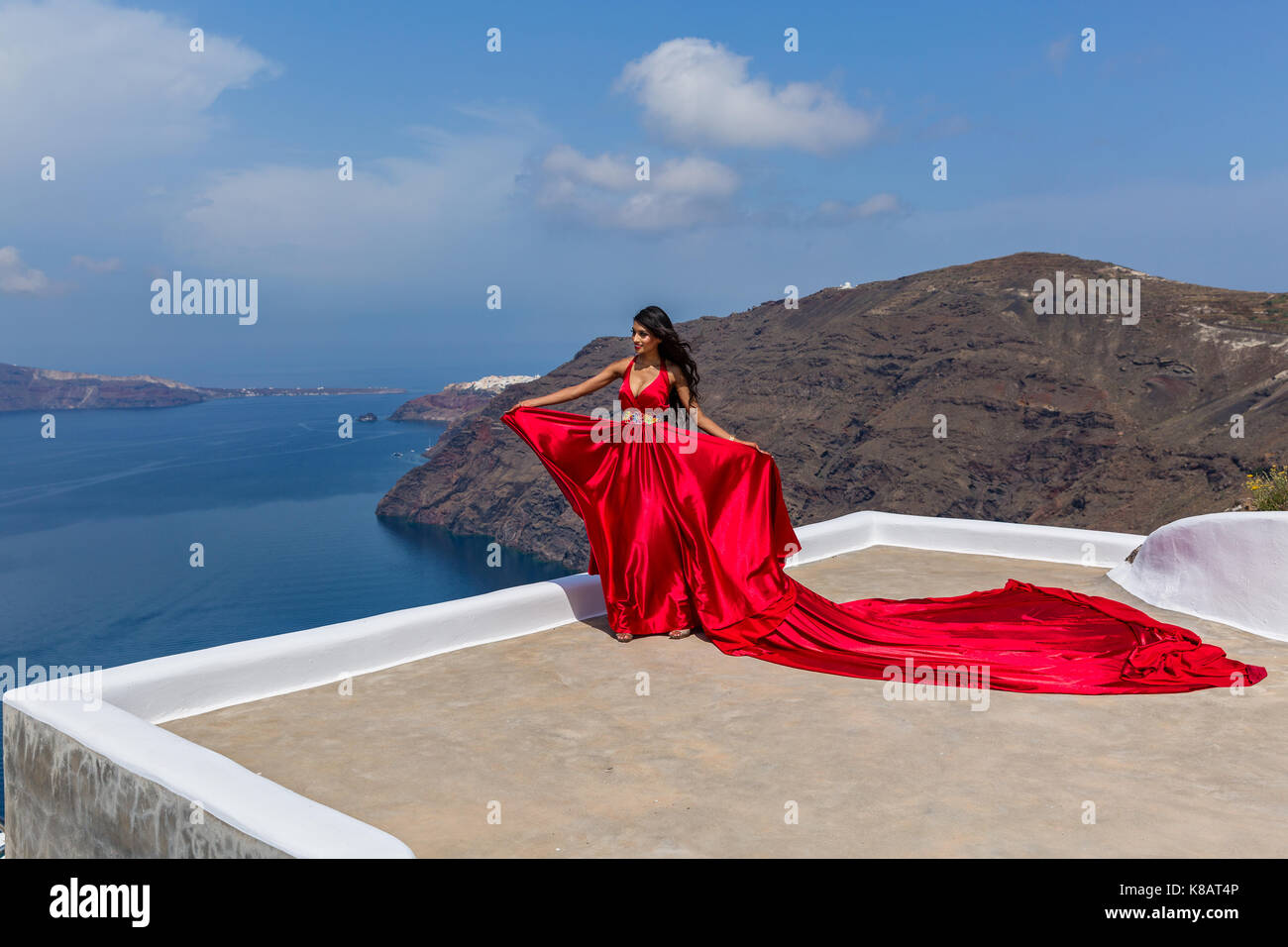 Donna in lungo abito rosso sul paesaggio di Santorini Foto Stock