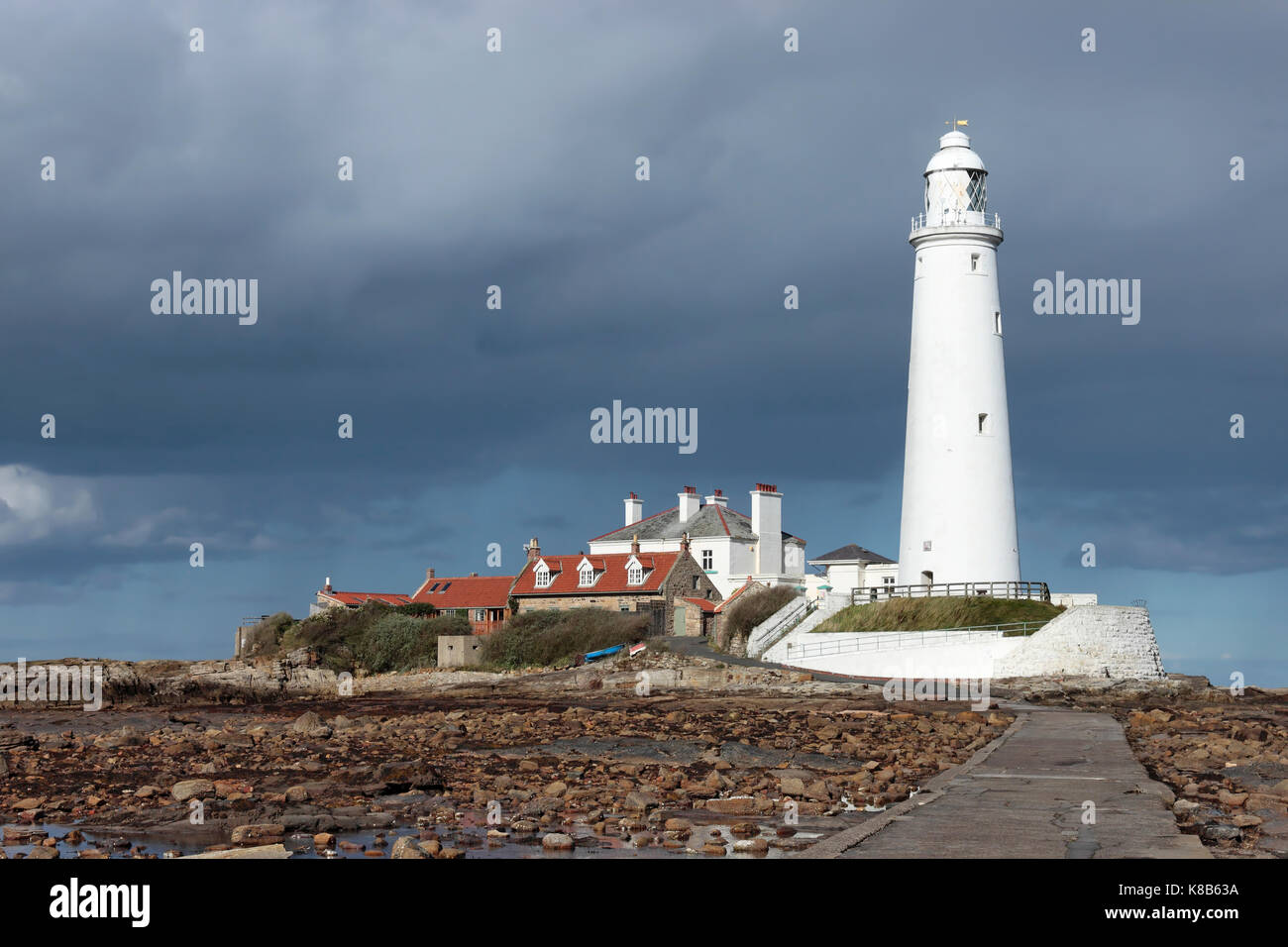 St Mary's Faro, St Mary's Island, Nr. Whitley Bay, a nord-est dell' Inghilterra, Regno Unito in condizioni di intensa luce solare diretta contro un cielo scuro con la bassa marea di sera presto Foto Stock