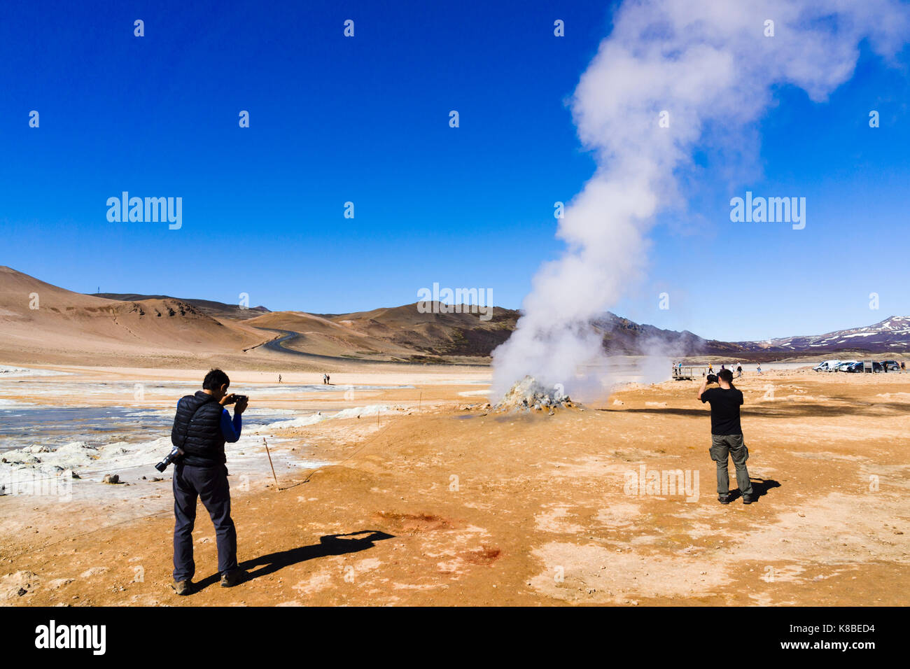 I turisti fotografano una fumarola fumante nella zona geotermica di Námafjall Hverir, Islanda Foto Stock