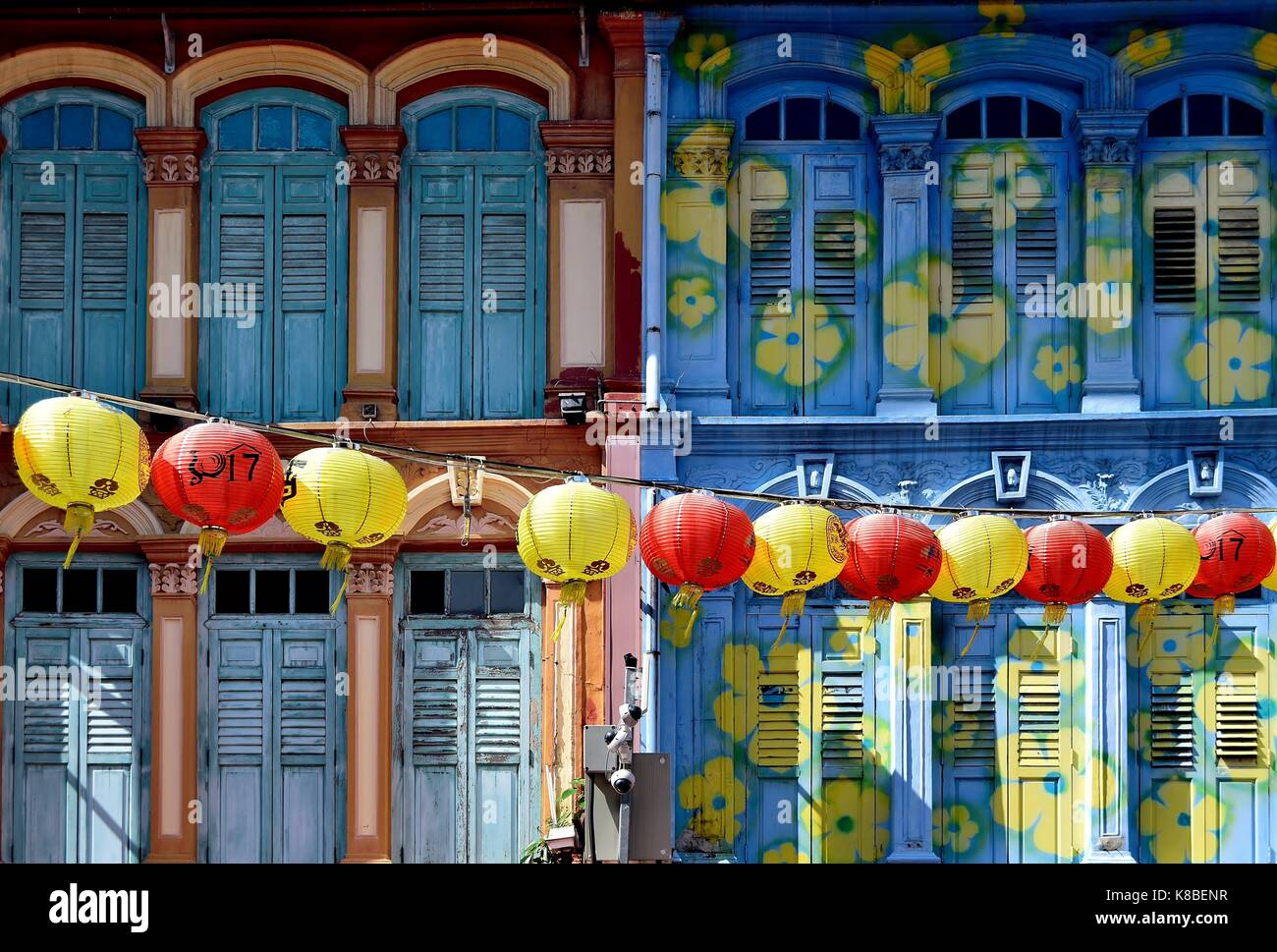 Una stringa di giallo e rosso lanterne cinesi appeso di fronte due negozio di colorate case per festeggiare il nuovo anno cinese a Chinatown Foto Stock