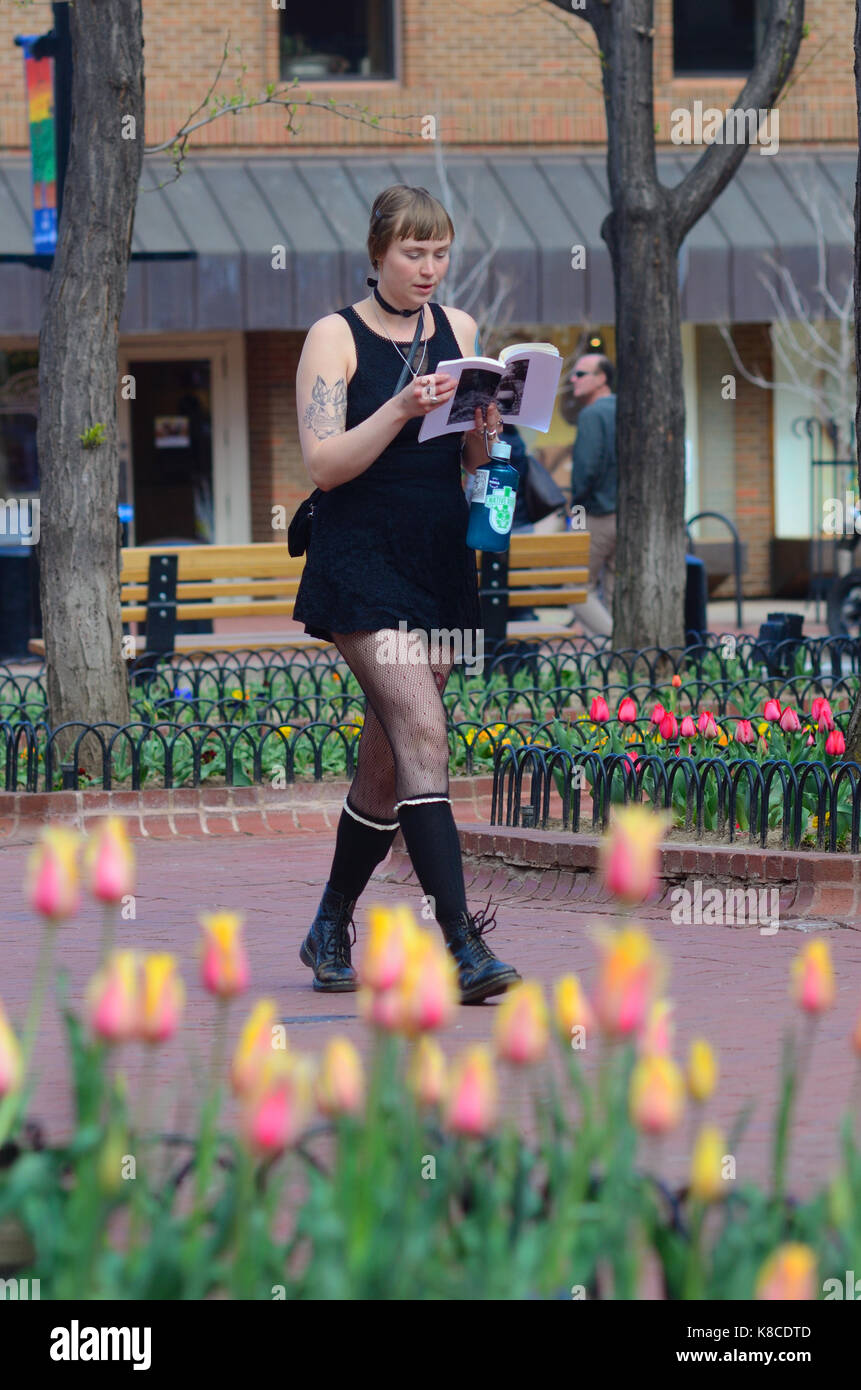 Giovane donna in abito corto legge mentre passeggiate tra i tulipani di Pearl Street Mall a Boulder, Colorado, Pearl St. Mall Foto Stock
