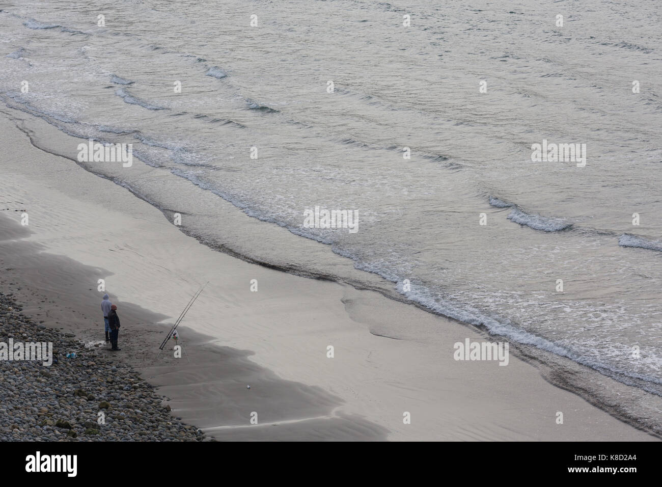 Due pescatori sulla spiaggia vicino al mare con aste, la pesca in mare in attesa di catture Foto Stock