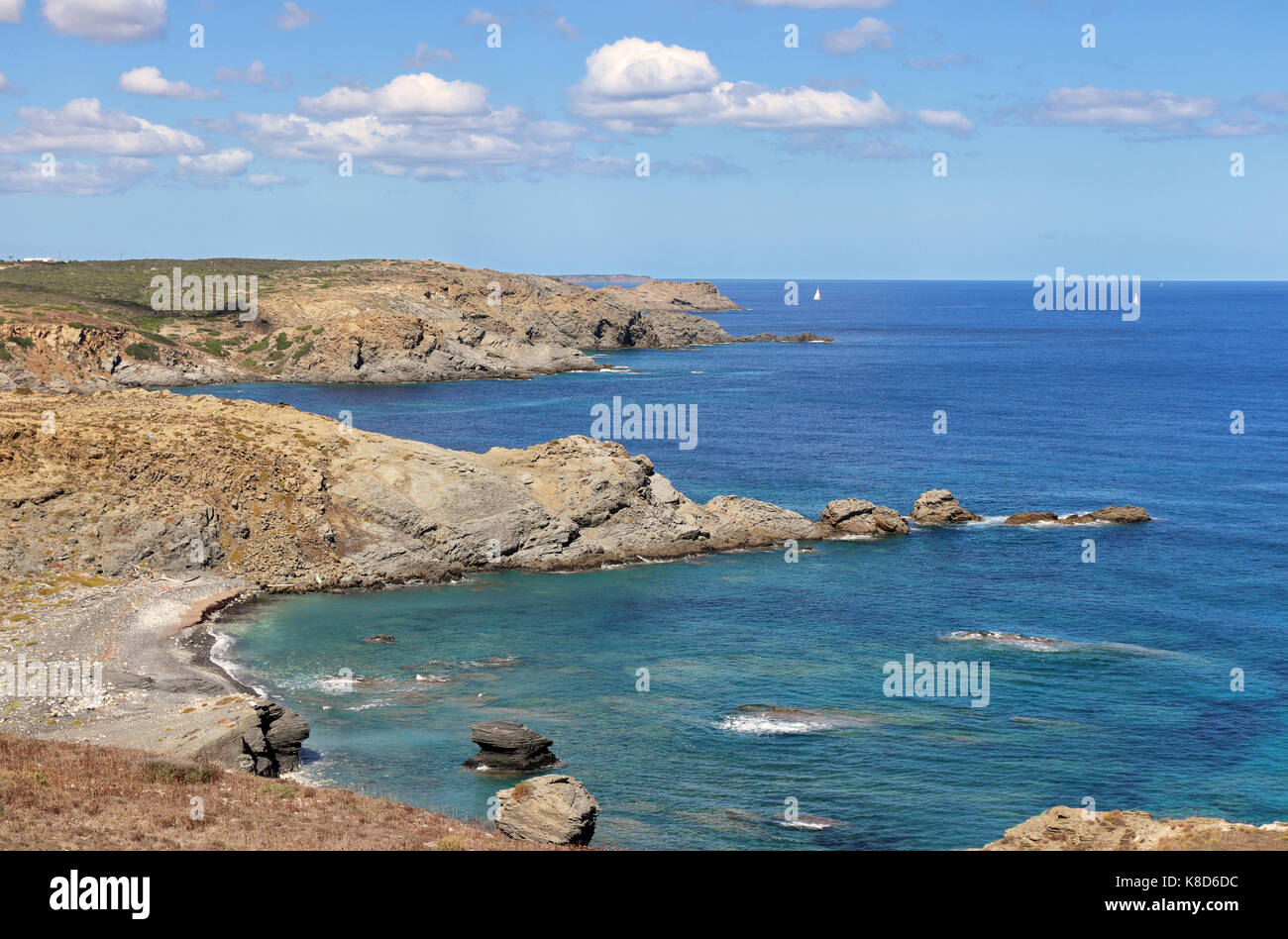 Vista costiera sull isola delle Baleari di Minorca nel mar mediterraneo con barche a vela in distanza Foto Stock