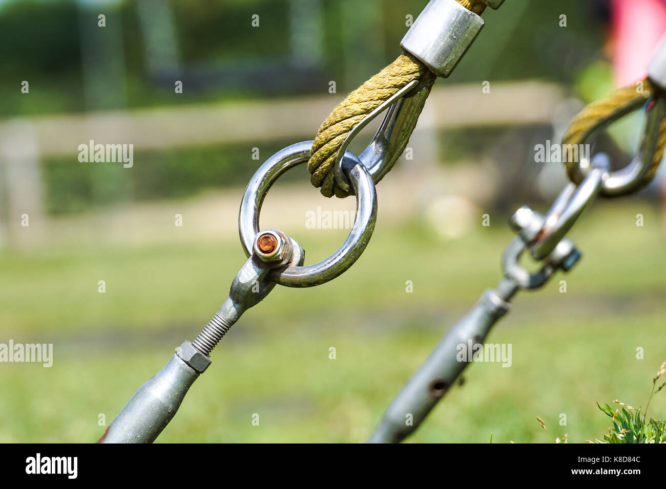 Fine della corda oscillante appendere su costruzioni di metallo in un parco. ruvida corda fine in cerchi di metallo e sicurezza il gancio a scatto Foto Stock