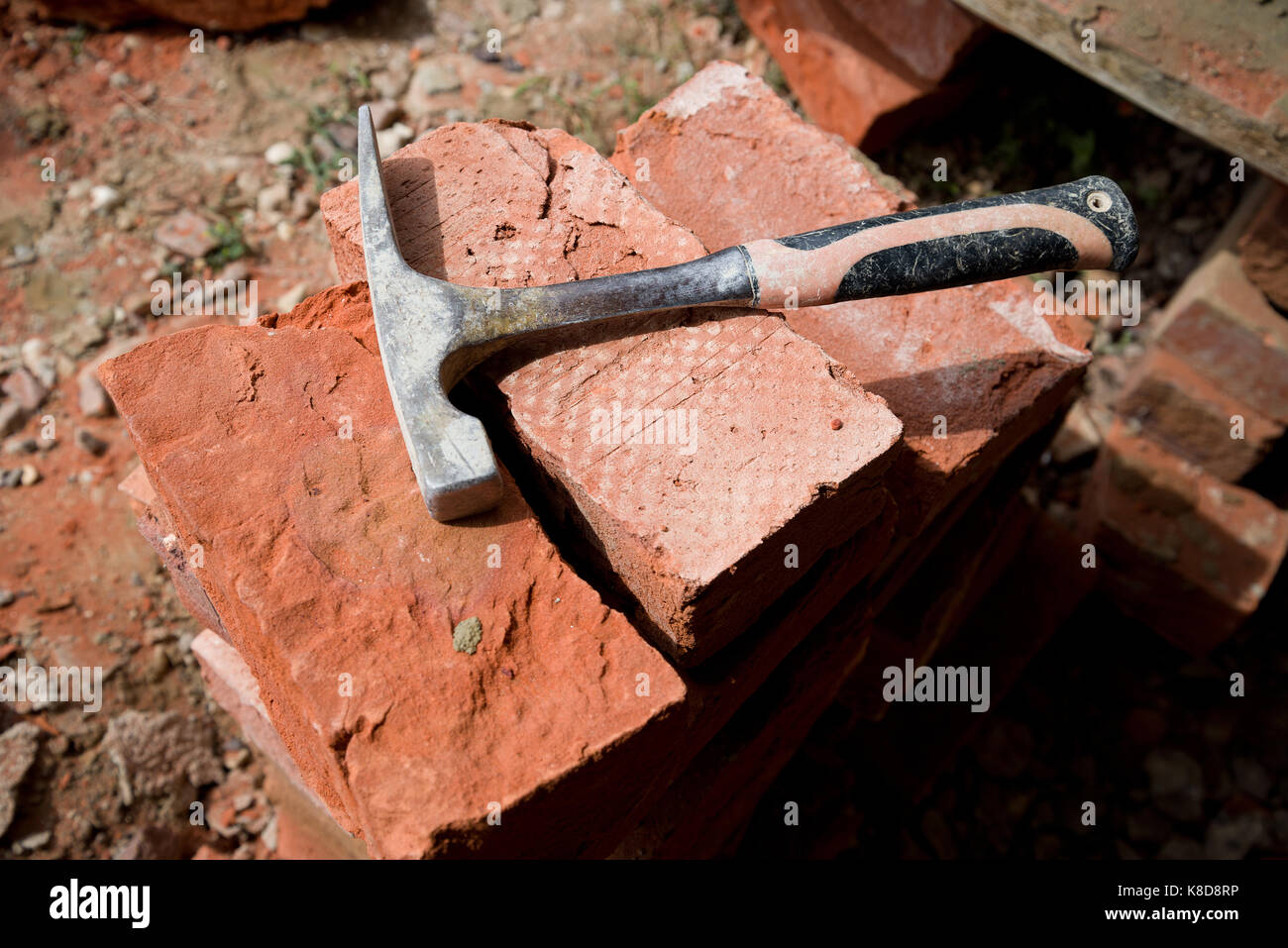 Pila di argilla rossa di mattoni fatti a mano con mattoni splitting martello. Foto Stock