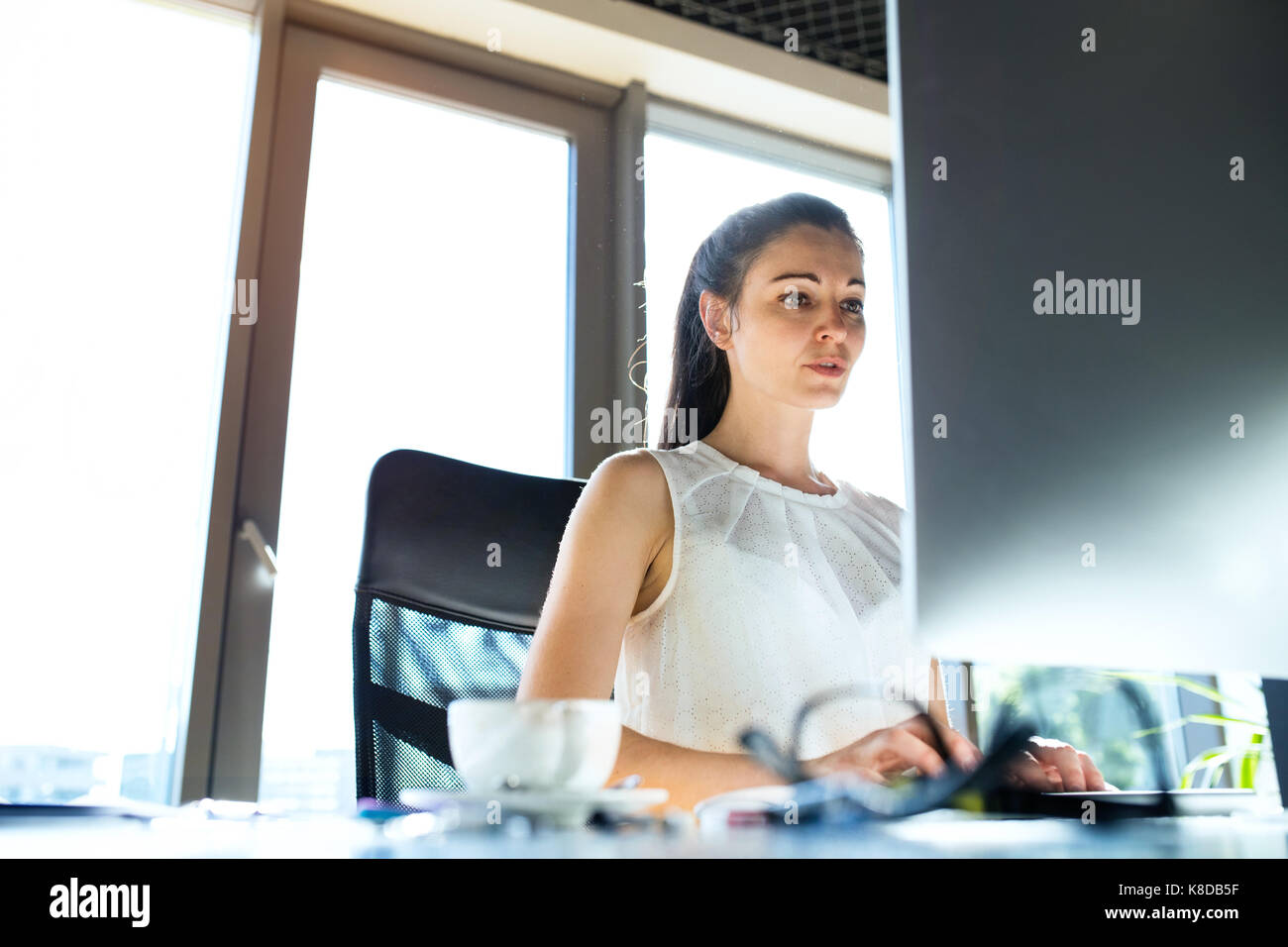 Imprenditrice con il computer nel suo ufficio, lavorando. Foto Stock
