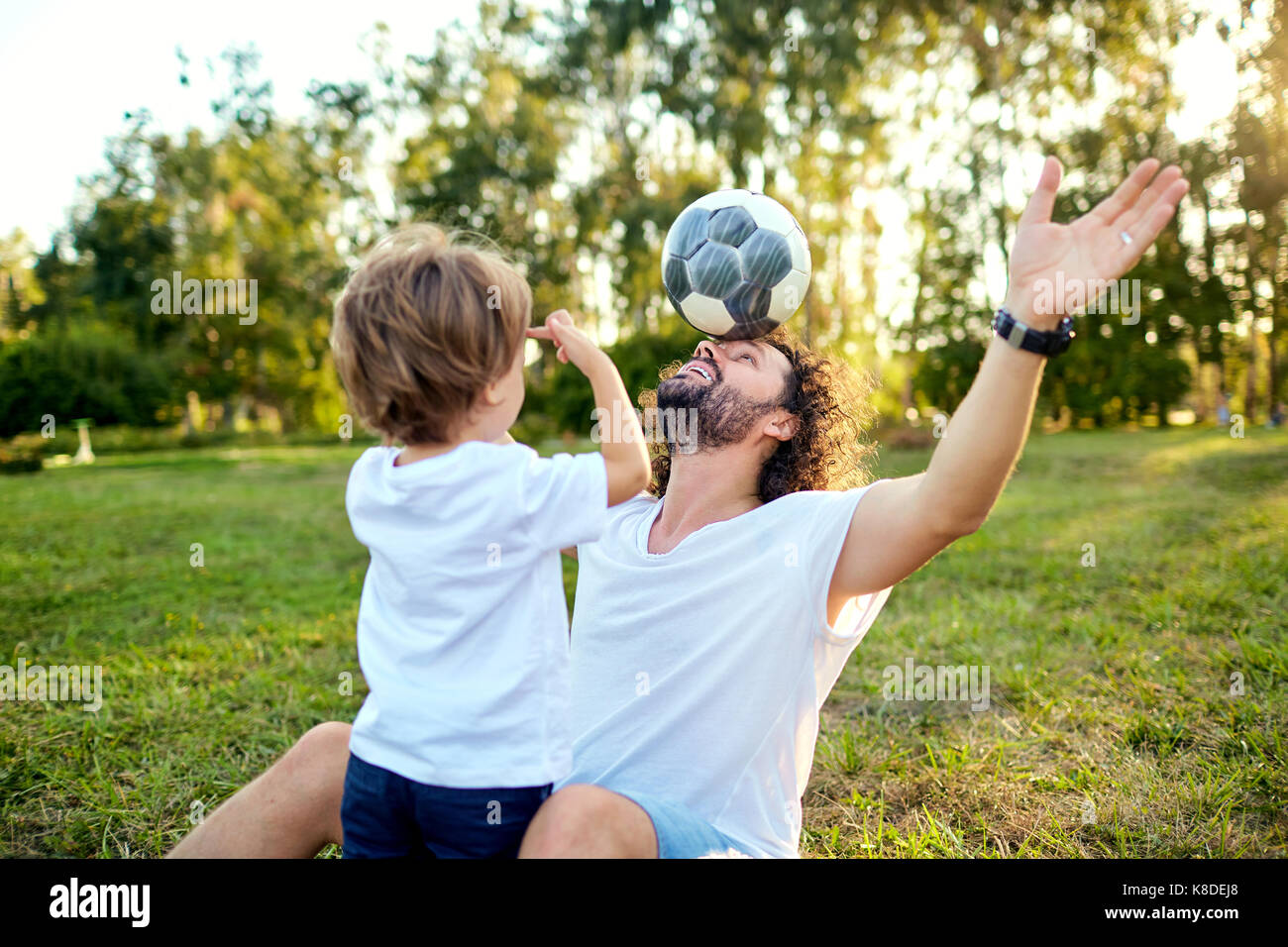 Padre figlio giocare con una sfera sull'erba nel parco. Foto Stock