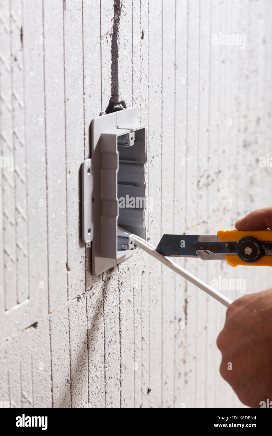 Un elettricista taglio attraverso il filo elettrico dopo l'installazione di un impianto elettrico utility box isolato in forma concreta in Ontario, Canada. Foto Stock