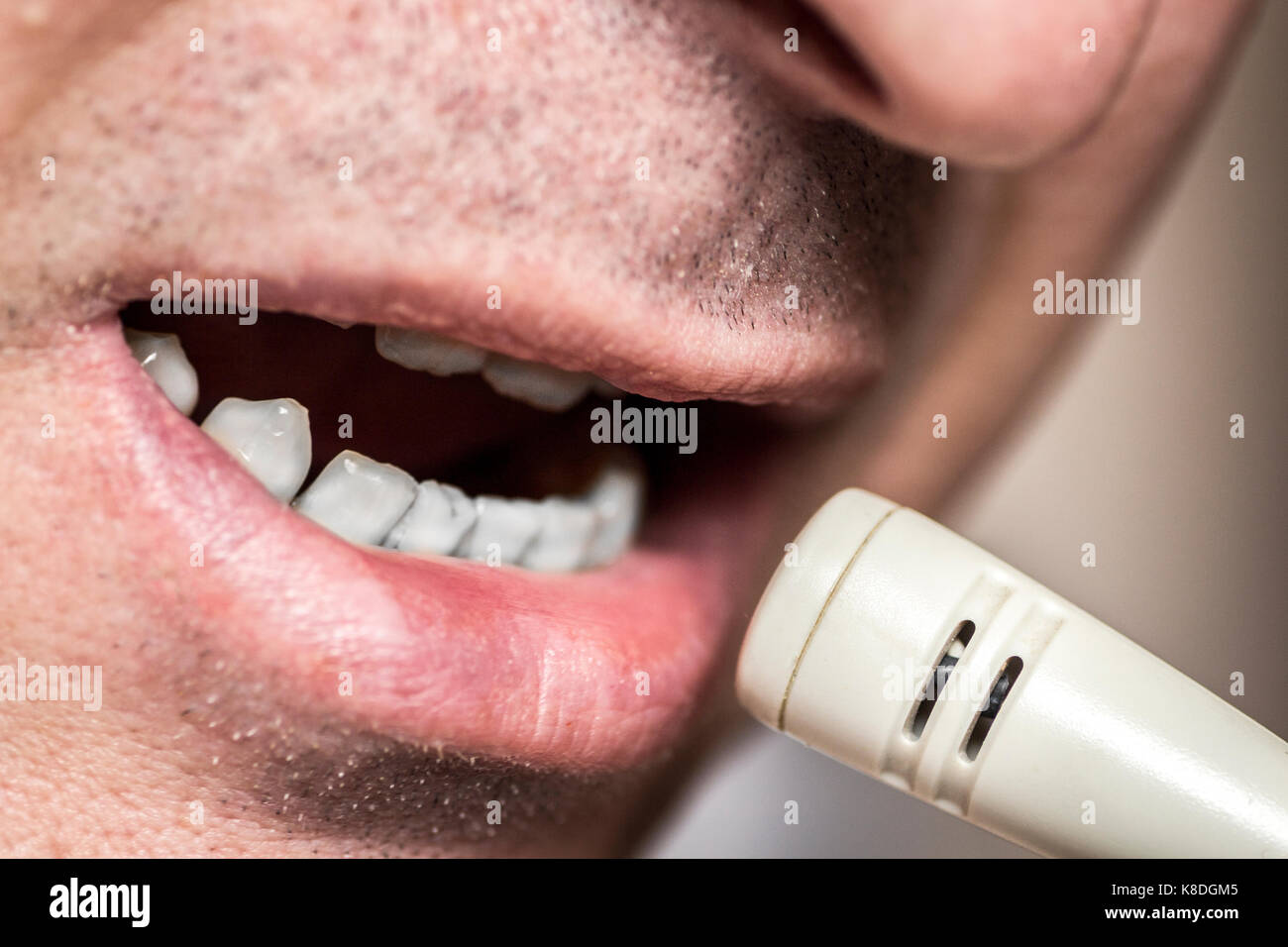 La parte inferiore della faccia stretta di un uomo parlando in un microfono. Foto Stock