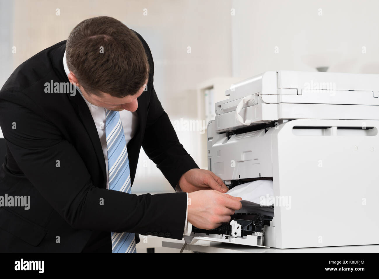Adulto medio imprenditore di rimuovere la carta bloccata nella stampante in ufficio Foto Stock