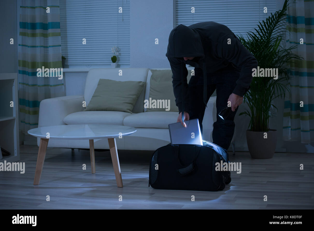Ladro maschio mettendo laptop in sacco a casa Foto Stock