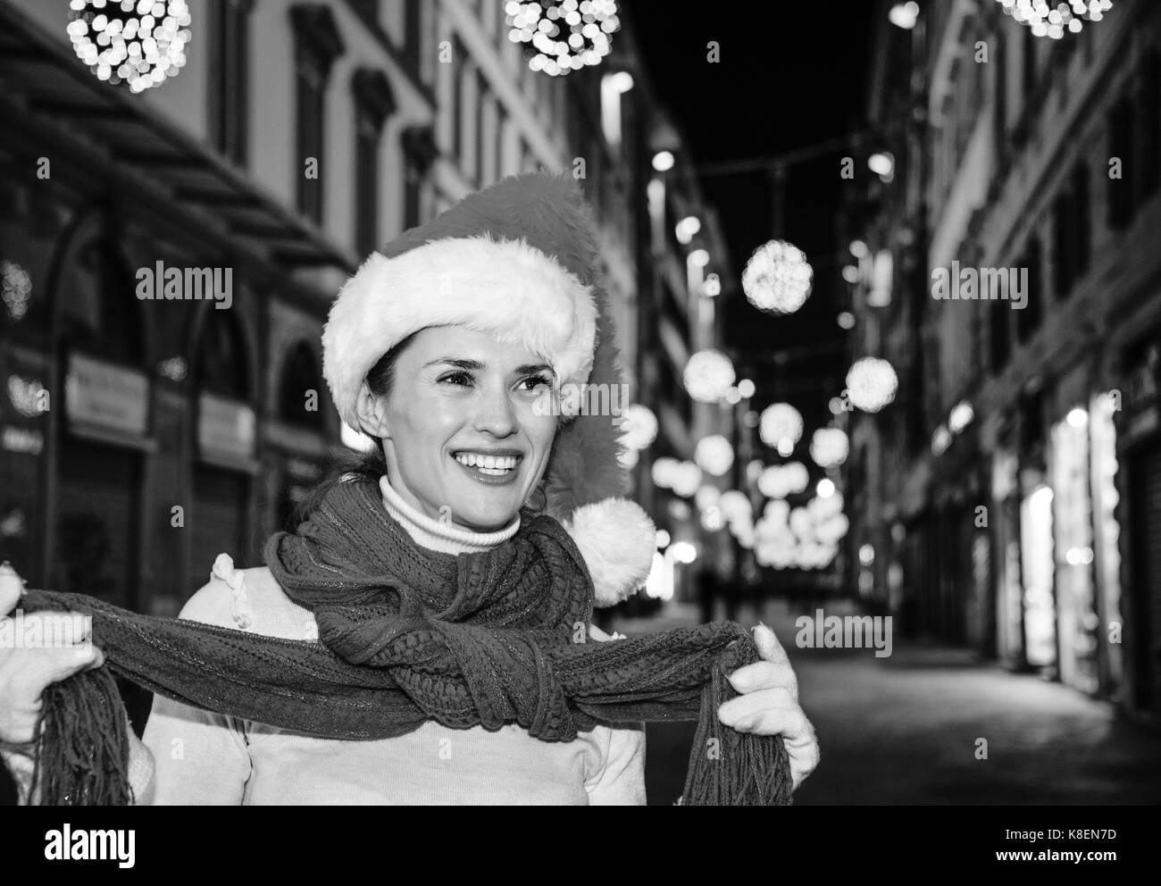 Viaggio pieno di ispirazione al tempo di Natale a Firenze. ritratto di felice donna moderna nel cappello di Natale A Natale a Firenze, Italia cercando in t Foto Stock