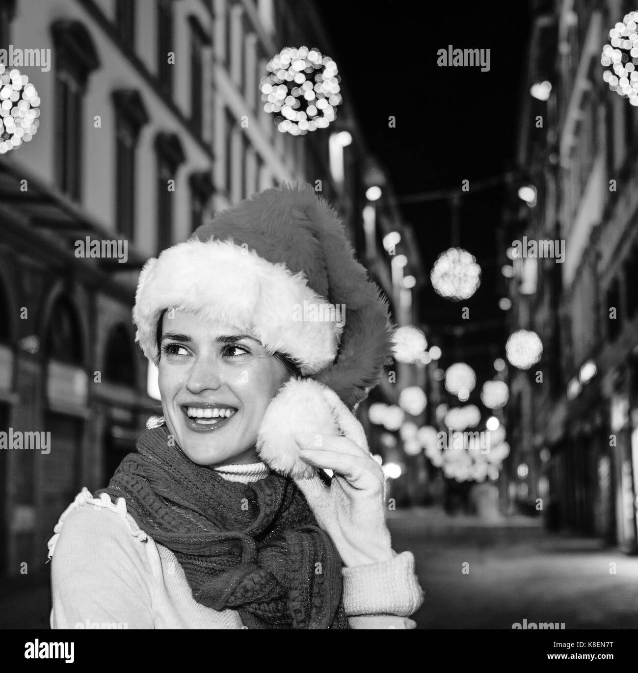 Viaggio pieno di ispirazione al tempo di Natale a Firenze. ritratto di sorridente donna moderna nel cappello di Natale A Natale a Firenze, Italia cercando in Foto Stock