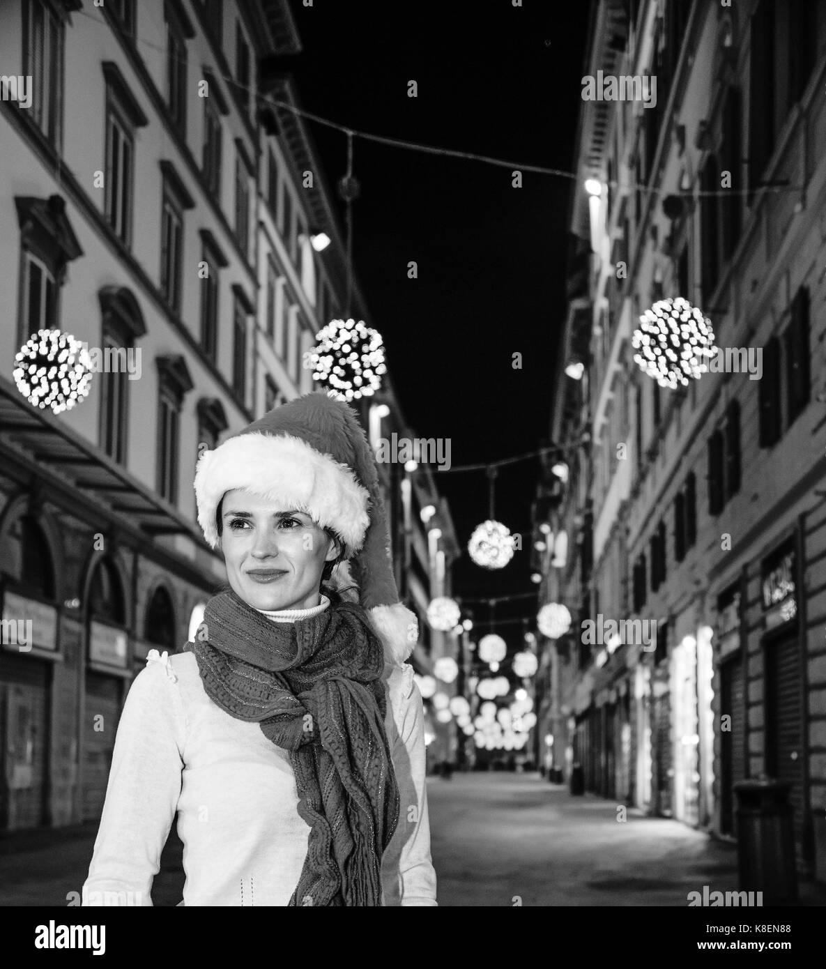 Viaggio pieno di ispirazione al tempo di Natale a Firenze. ritratto di sorridente donna moderna nel cappello di Natale A Natale a Firenze, Italia cercando in Foto Stock