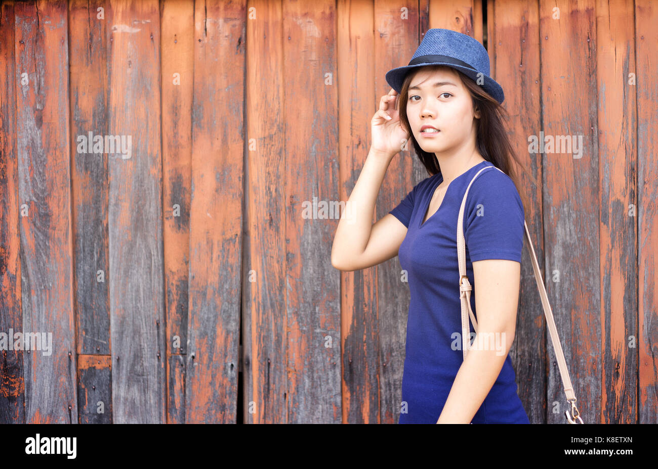 Asian lady modello con vestito blu e il cappello in estate la parte anteriore del vecchio rosso Sfondo legno Foto Stock